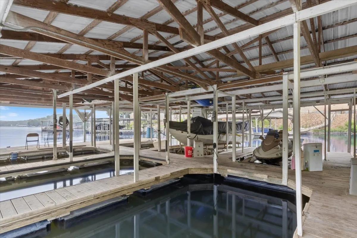 This image features several boats moored at wooden docks, calm water gently reflecting the sky, and a tranquil lakeside atmosphere. The docks are surrounded by lush greenery, evoking a peaceful lakeside retreat perfect for fishing and boating.
