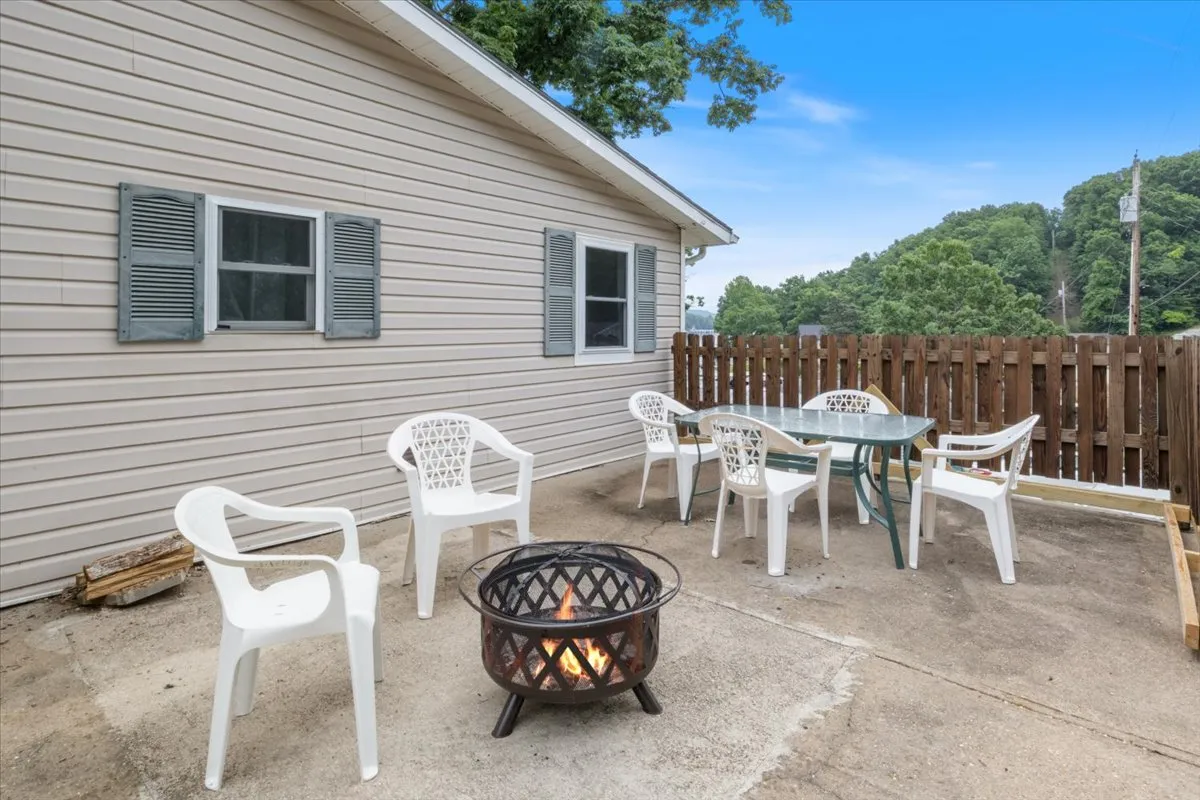 A welcoming fire pit area surrounded by outdoor seating and lush greenery, designed for gatherings and relaxation. The seating arrangement is perfect for groups to share stories or roast s'mores under the stars.