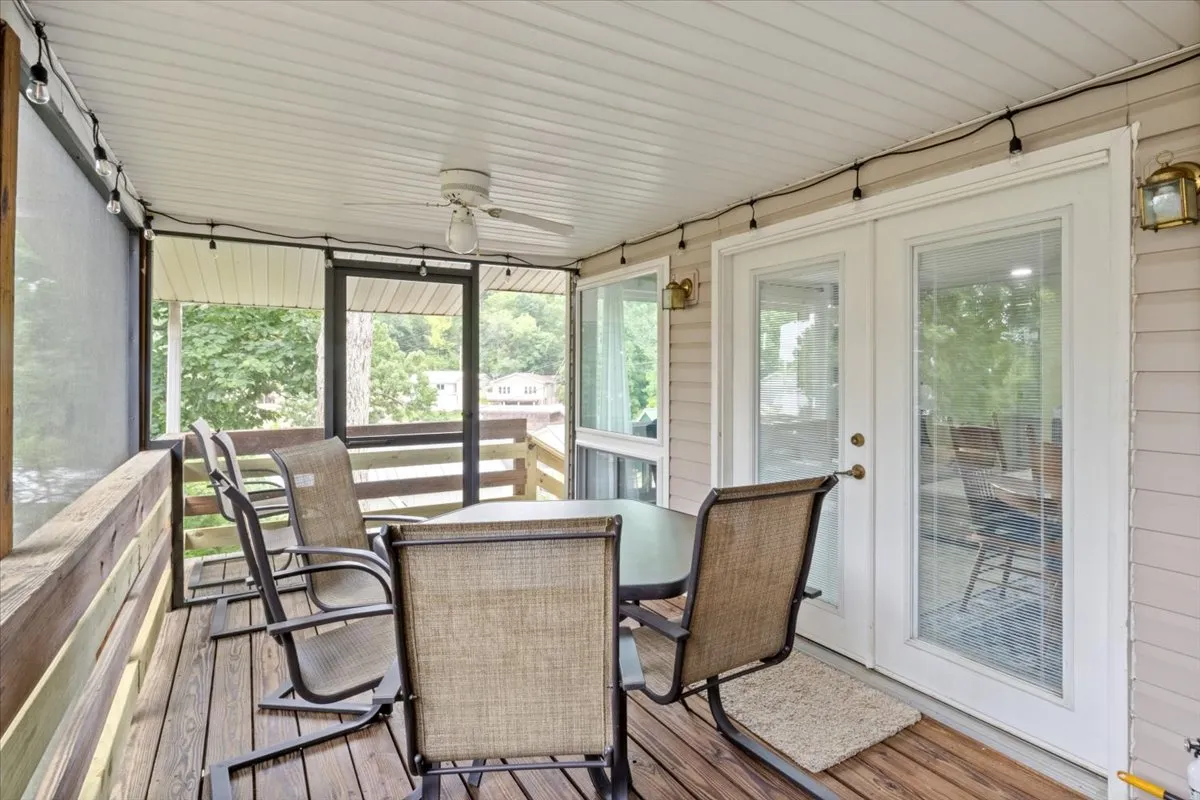 A dining area with a table and several chairs positioned near glass doors offering a sweeping outdoor lake view. Soft daylight streams in, creating a relaxed, scenic ambiance perfect for enjoying meals with a view.