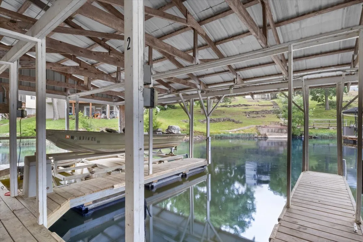 A tranquil lakeside scene featuring boats docked at a wooden pier, set against calm water and a peaceful shoreline. The space invites boating, fishing, or sunset cruises with friends or family.